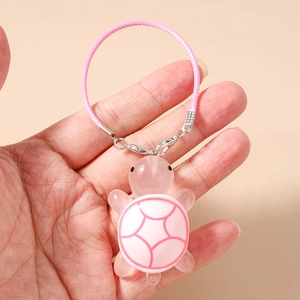 Close-up of pink turtle phone charm with resin shell and hand-woven cord strap