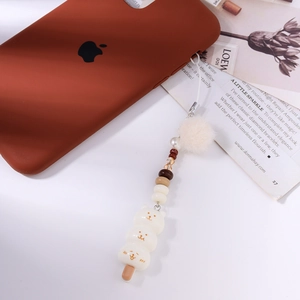 Détail de breloques ours et pompon en peluche sur une lanière de téléphone créative