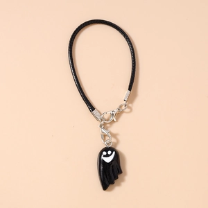 Detail of black ghost charm with white smile and braided rope for phone accessory