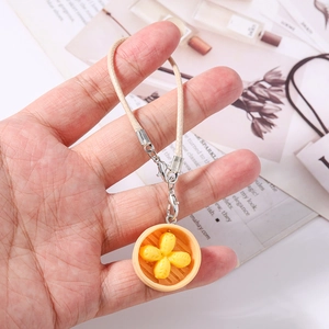 Close-up of a miniature food charm featuring a detailed steamed dumpling in a tiny basket