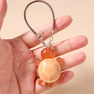 Detailed view of turtle charm with translucent resin limbs and amber-colored finish