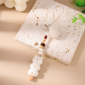 Détail d'un charmant dango ours à 3 couches avec pompon rose en fausse fourrure et perles