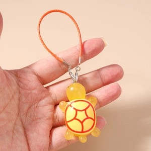 Detail of yellow turtle charm with red shell pattern and orange woven lanyard