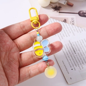 Detail of beaded bee keychain with yellow striped body and translucent blue wings