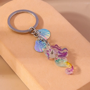 Macro view of gradient resin seahorse keychain with iridescent shell charms and metal ring