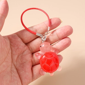 Detail of cute red and pink resin turtle charm being held to show compact size