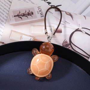 Macro shot of a cute brown turtle resin pendant with an orange geometric shell pattern