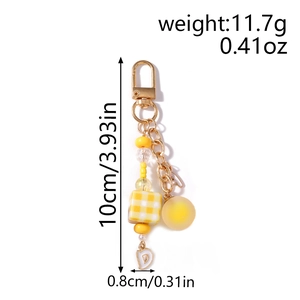 Detail of yellow beaded keychain with lobster clasp, checkered bead and metal letter charms