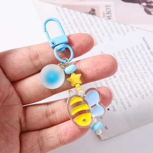 Cartoon bee beaded keychain with blue stars and pearls on a magazine background