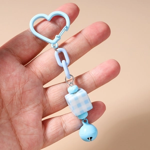 Detail of blue heart-shaped clasp keychain with a checkered cube and a small bell