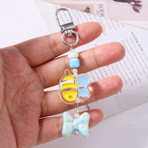 Detail of bee and green bow beaded keychain with silver metal clasp and colorful pearls