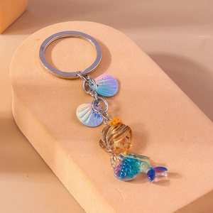 Detail of mermaid keychain with golden crown and shimmering iridescent shell charms
