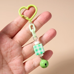 Detail of green acrylic chain keychain with checkered bead and metal bell attachment