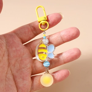 Close-up of beaded bee keychain with yellow hook and blue crackle beads on pink background