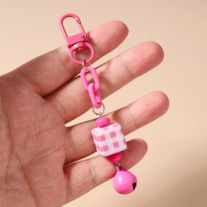 Detailed view of pink chain keychain featuring check cube bead and metal bell charm