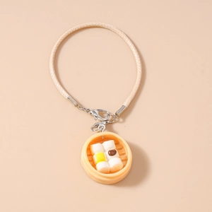 Macro shot of miniature bamboo steamer pendant with faux dumplings on leather phone strap