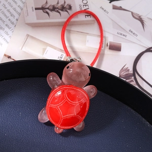 Detailed view of turtle charm in pink resin with red shell on a woven cord loop