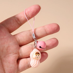 Close-up of pink peanut pendant with cute face and matching bell on a phone strap