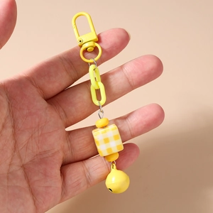 Detail of yellow chunky chain keychain with checkered cube bead and small metal bell charm