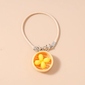 Detailed macro view of creative miniature dumpling steamer charm on woven bracelet cord
