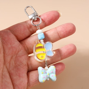 Detailed close-up of cartoon bee keychain with resin bow and silver spring clip holder