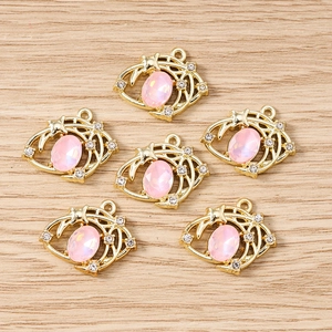 Détail de pendentifs étoile et lune dorés avec pierres roses et strass blancs brillants