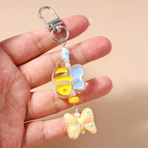 Detail of bee keychain with light blue stars, white pearls and a yellow polka dot bow