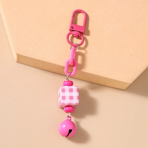 Detailed shot of pink plastic chain keychain with checkered cube bead and small bell