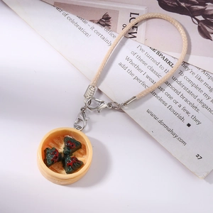 Detail of miniature food phone charm featuring green dim sum in a small yellow steamer
