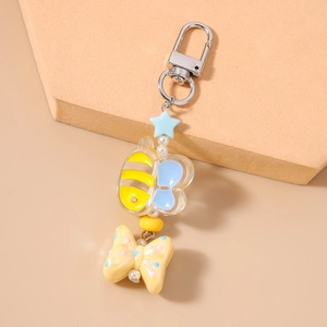 Close-up of beaded bee keychain with yellow bow and blue star on geometric stand