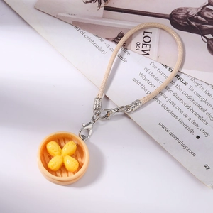 Detailed macro view of a miniature food charm featuring golden buns in a small steamer basket