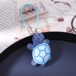 Detail of blue resin turtle charm featuring white geometric shell and silver metal clasp