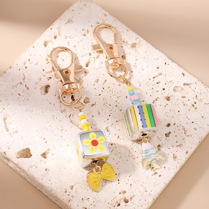 Detail of beaded keychain charms with yellow bow and blue fish on a textured stone
