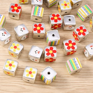 Macro detail of colorful floral and cartoon puppy patterns on silver cube beads