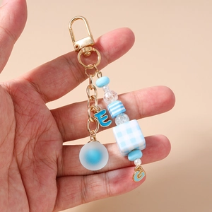 Detail of beaded keychain with blue square beads, gold clasp and blue letter E charm