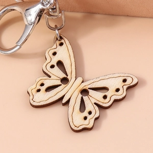 Fashionable laser-cut wooden butterfly keychain with a silver metal clasp on pink background