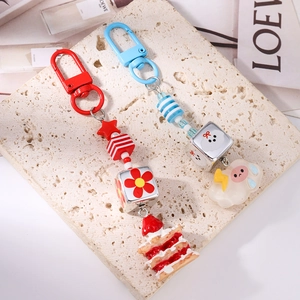Détail de porte-clés à perles rayées colorées avec breloques étoile, gâteau et agneau