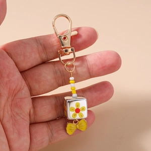 Detailed view of handmade beaded keychain featuring a floral cube and yellow ribbon