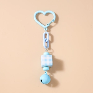 Detail of light blue keychain with heart clasp, checkered cube bead, and bell charm