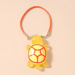 Close-up of yellow turtle charm with orange woven strap and silver clasp detail