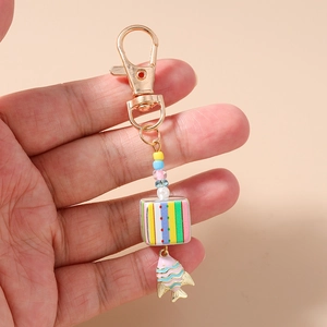 Close-up of beaded keychain with colorful cube and goldfish pendant in a soft hand grip