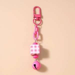 Detailed view of pink keychain with checkered cube charm and small bell accessory