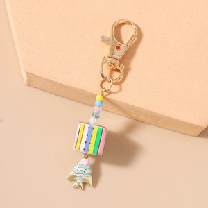 Detailed close-up of rainbow beaded keychain with striped square charm and gold fish pendant