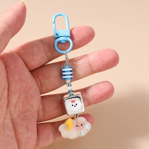 Détail d'un porte-clés bleu ciel avec des perles de nuages et motifs à rayures