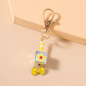 Detail of yellow bow pendant and floral bead on a gold-plated stylish keychain