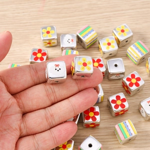 Macro detail of colorful square metal beads with floral and cartoon dog patterns