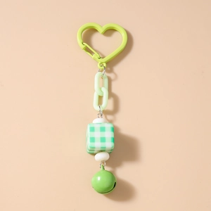 Detail of green heart carabiner with acrylic chain, checkered bead, and bell keychain charm