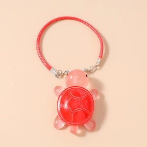 Detail of red translucent turtle charm with white crackle patterns and red braided rope