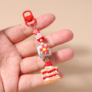 Détail du porte-clés gâteau aux fraises avec perles rayées et étoile rouge sur fermoir