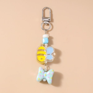 Detail of beaded cartoon bee keychain with blue wings and a green polka dot bow charm